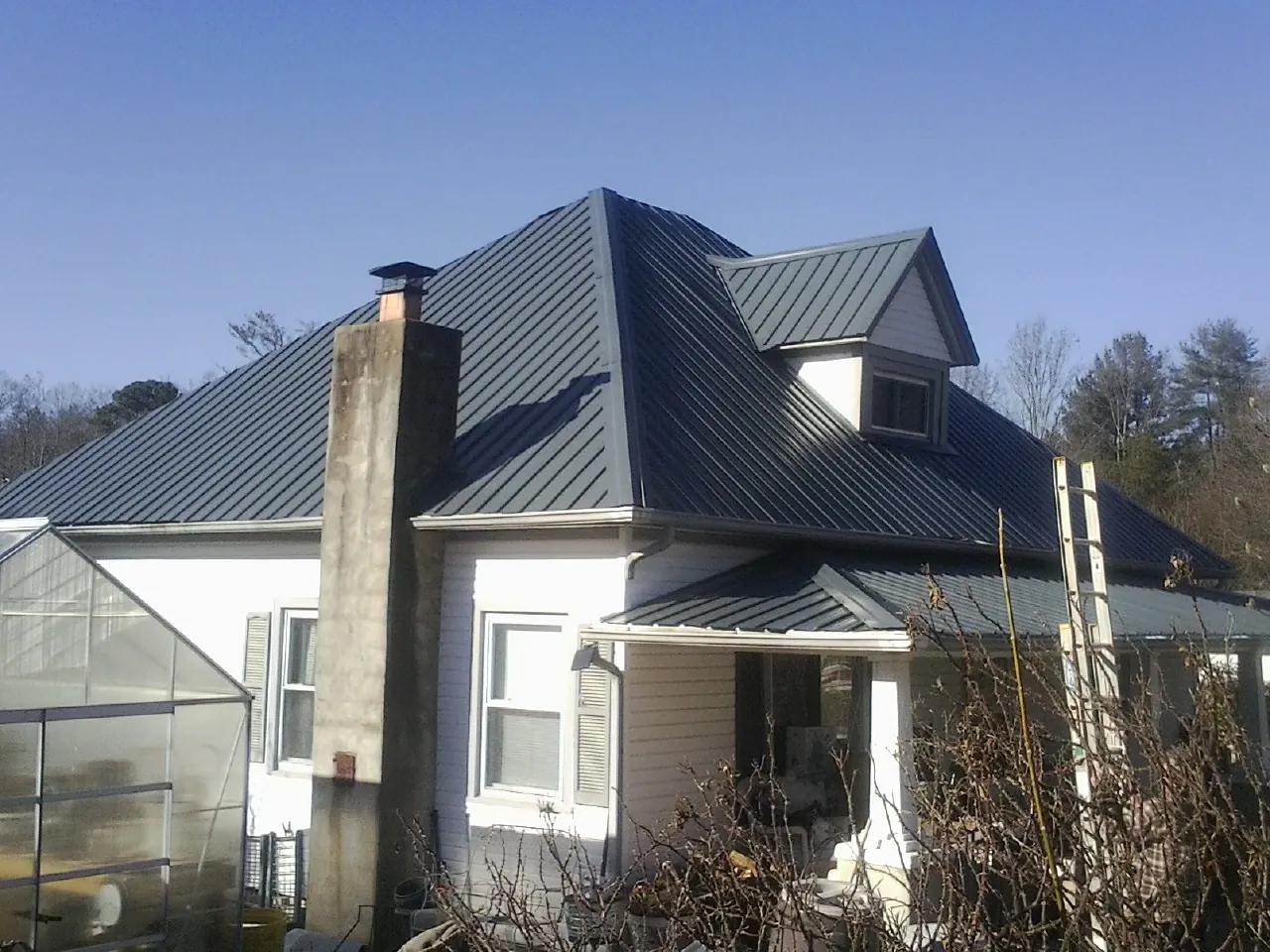 Dark blue standing seam metal roof on a white farmhouse with dormer — Slate & Tile Roof Repair by Roofing Brothers in Phoenicia