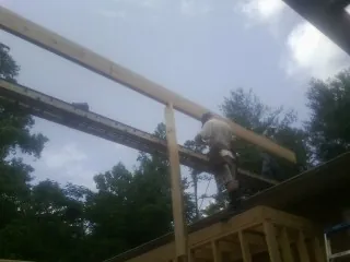 Carpenter setting a ridge beam over a new addition frame — Ice Dam Removal by Roofing Brothers in Phoenicia