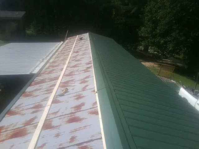 Old rusted panels beside newly installed green metal roofing — Wind Damage Roof Repair by Roofing Brothers in Phoenicia
