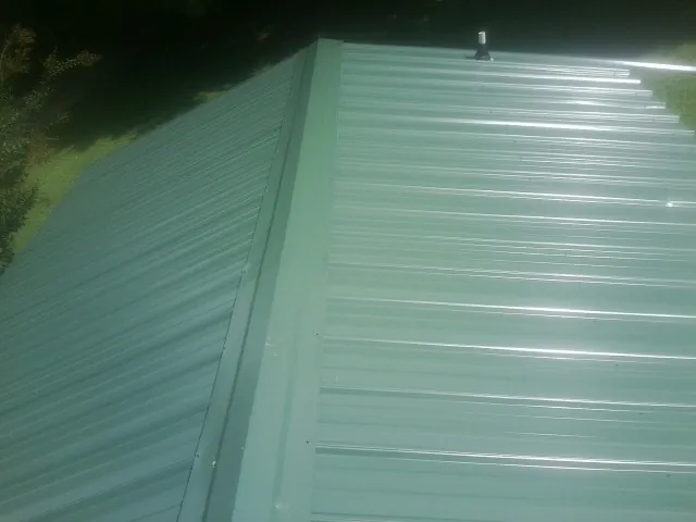 New green metal panels meeting at the ridge of a roof — Flat Roof Repair work by our crew in Phoenicia