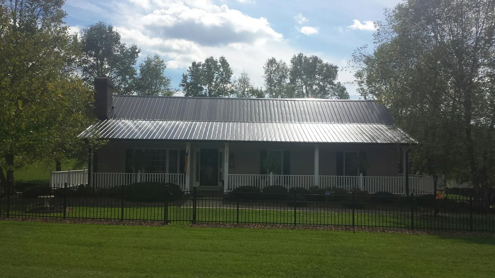 Gray metal roof on a brick ranch with a full width front porch — Gutter Guard Installation work by our crew in Phoenicia