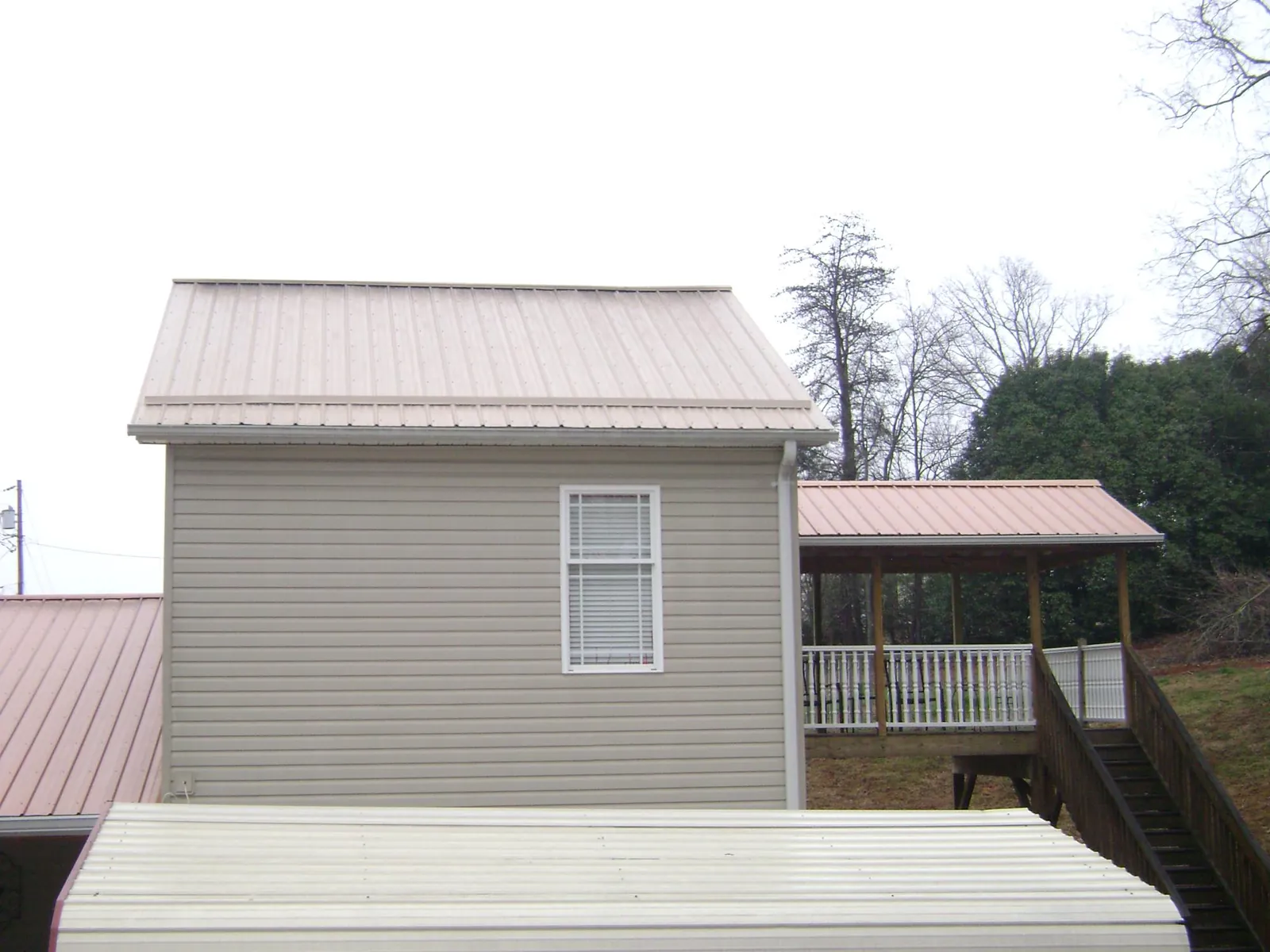 Tan metal roofs on a two story addition and attached porch, from a Roof Replacement job in Phoenicia